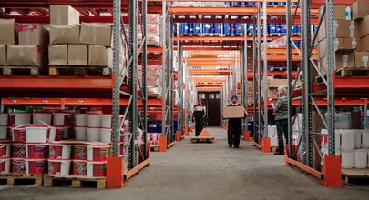 Workers moving pallets down the racking aisles of a working warehouse