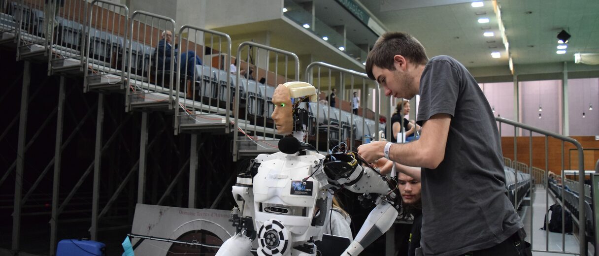 An engineer working hands-on with a humanoid robot rig during a demonstration capture session